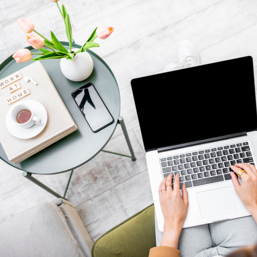 Photography Branding, Mac Laptop on someone lap, they are typing on computer by a table with a brand book and flowers