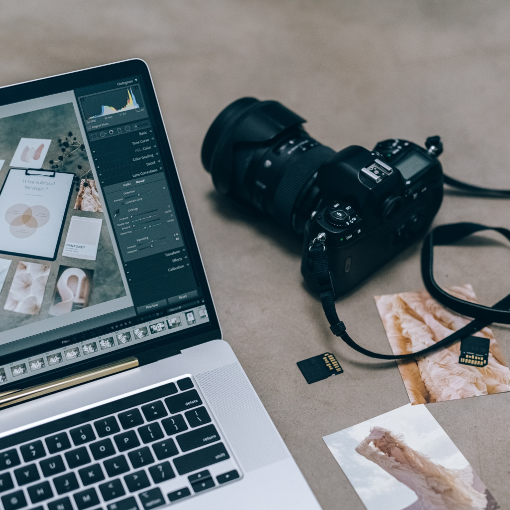 Photography services example, this shows a camera next to computer editing photos, there a sd card and pens next to it